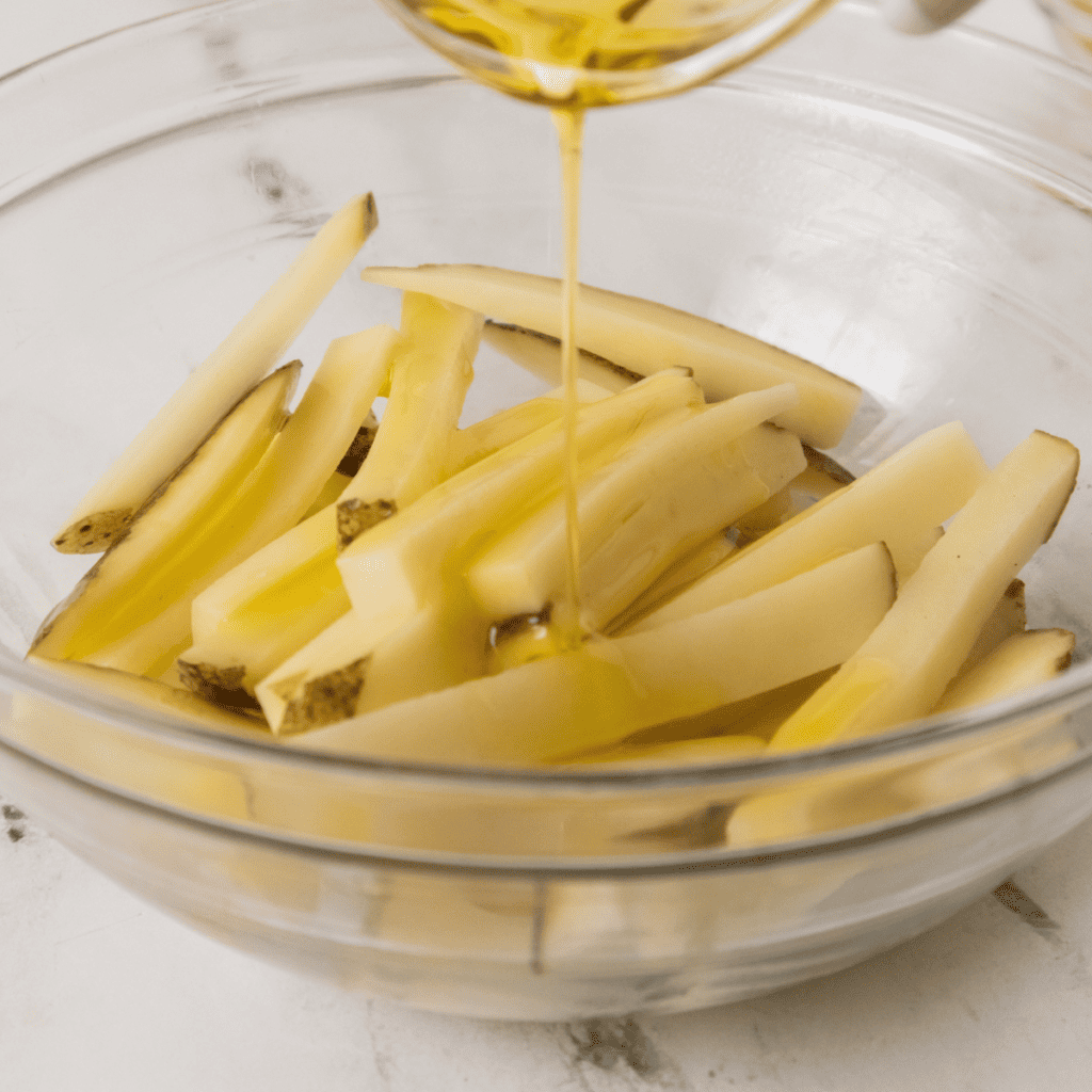 Tossing the fries in a bowl with oil and Cajun seasoning, ensuring an even coating.