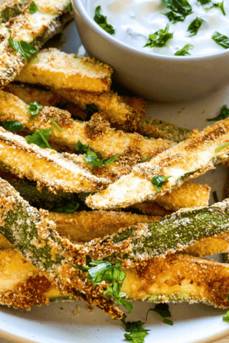 A plate of crispy, golden-brown Copycat Carrabba’s Zucchini served with marinara sauce for dipping.