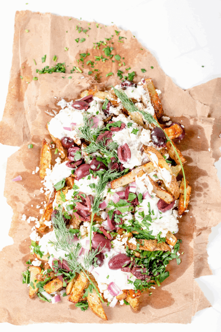 Golden air fryer Greek fries topped with crumbled feta and fresh herbs, served as a Mediterranean side