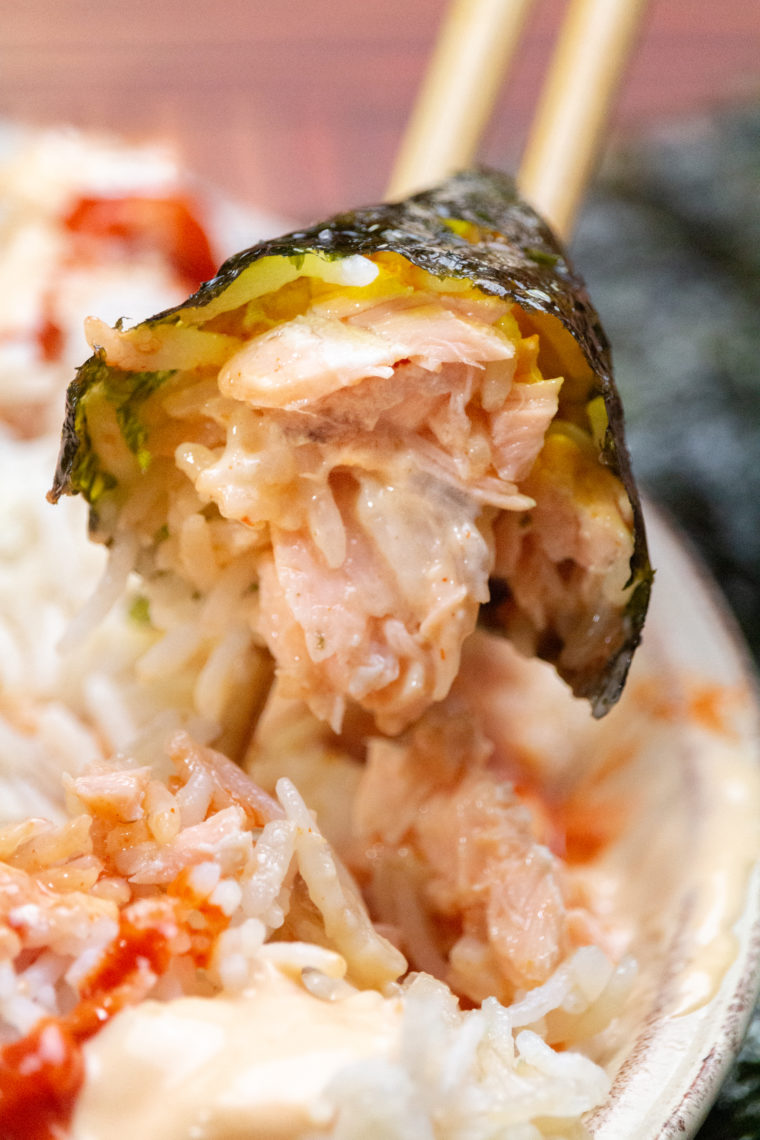 Close-up of homemade salmon sushi rolls with avocado and sticky rice on a bamboo mat