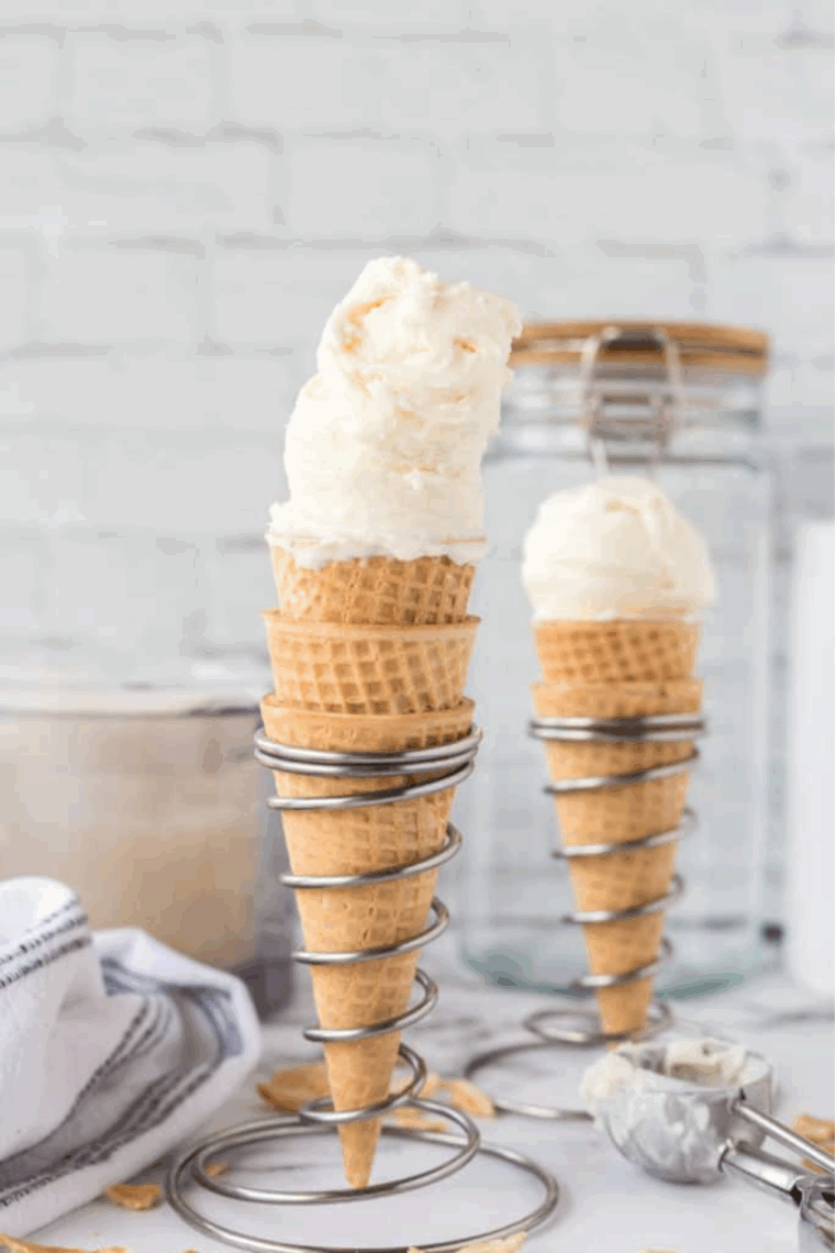 Two scoops of homemade Ninja Creami vanilla bean ice cream in a waffle cone, showing its creamy speckled texture