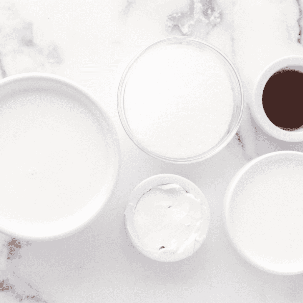 Cream cheese, sugar, vanilla bean paste, heavy cream, and milk laid out to make vanilla bean ice cream