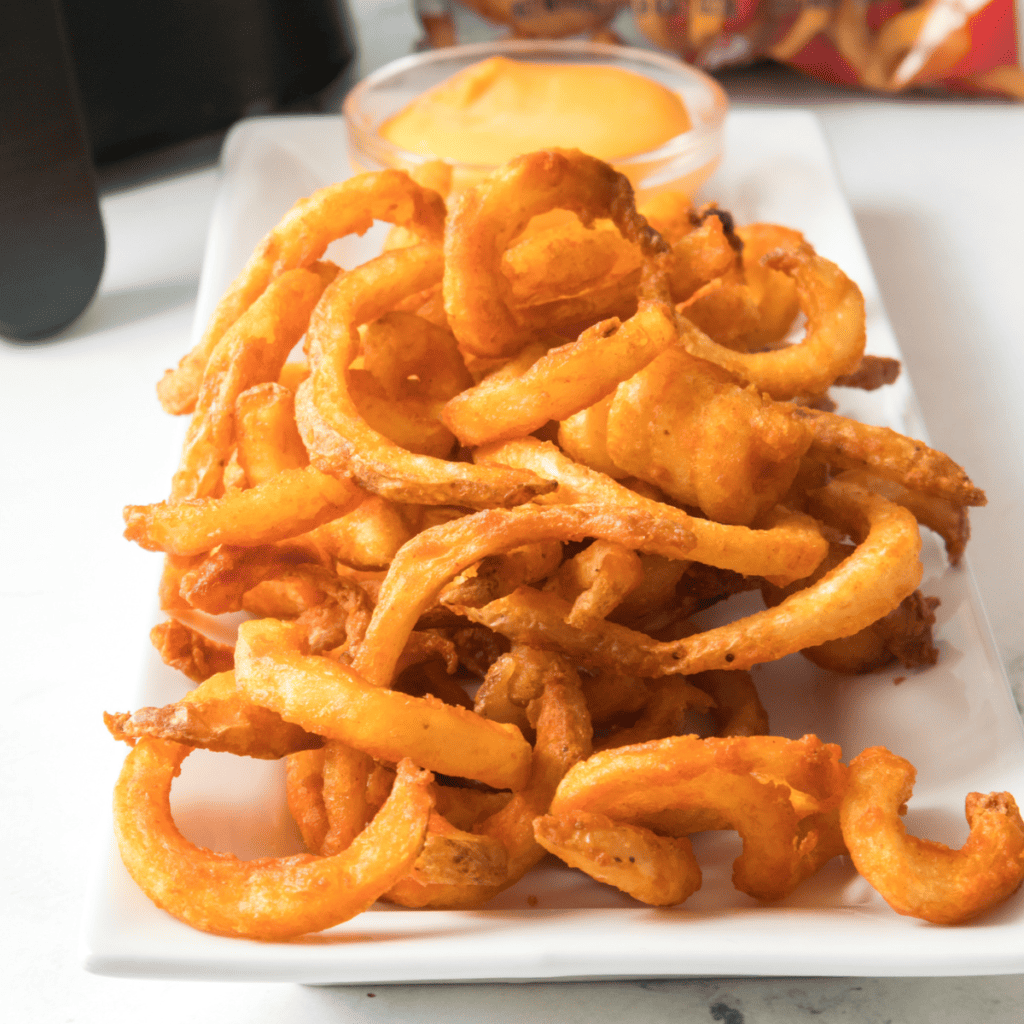 Plate of cooked arby's fries on the counter with dipping sauce.
