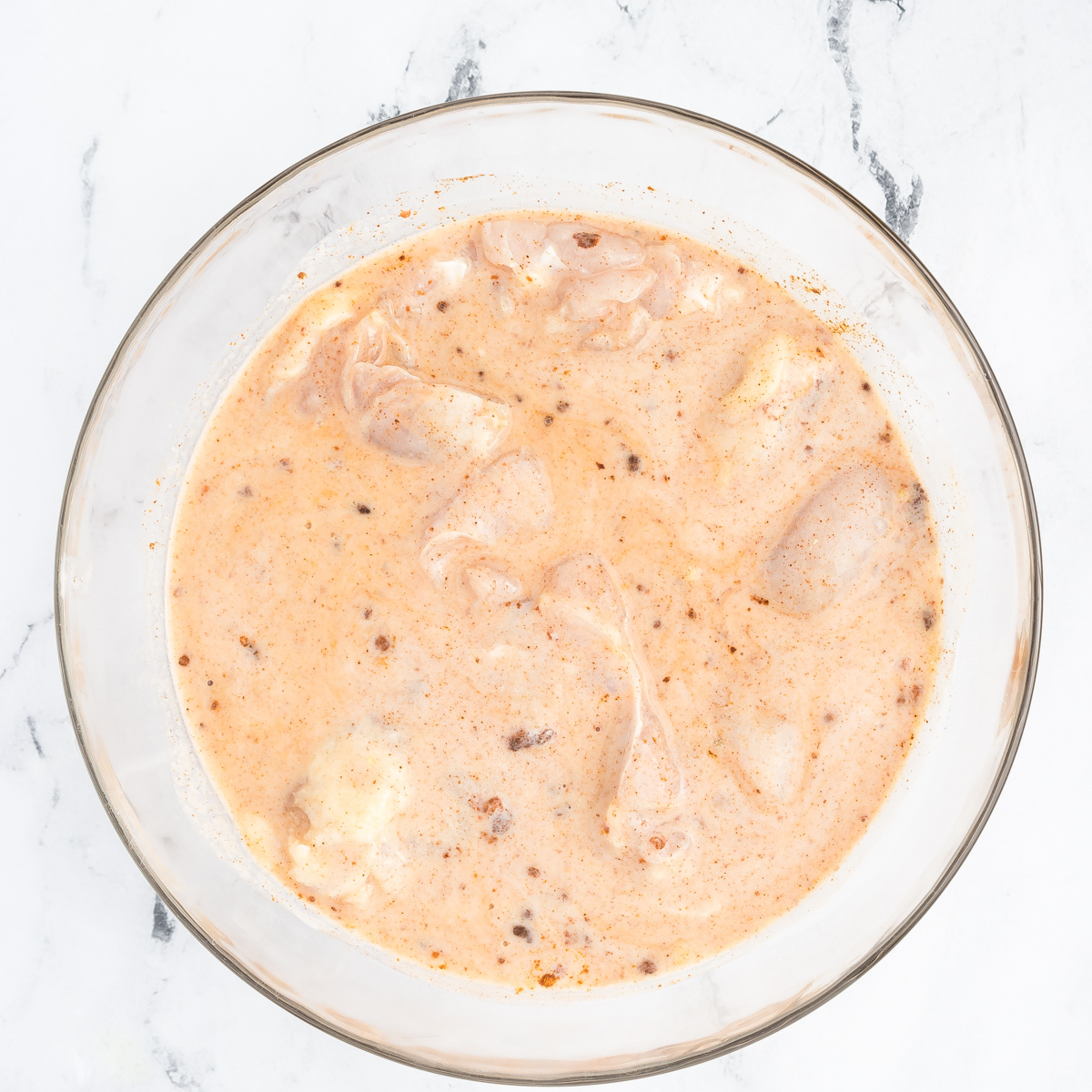 Coated chicken thighs placed in a single layer inside a preheated air fryer basket set to 400°F, ready for cooking.