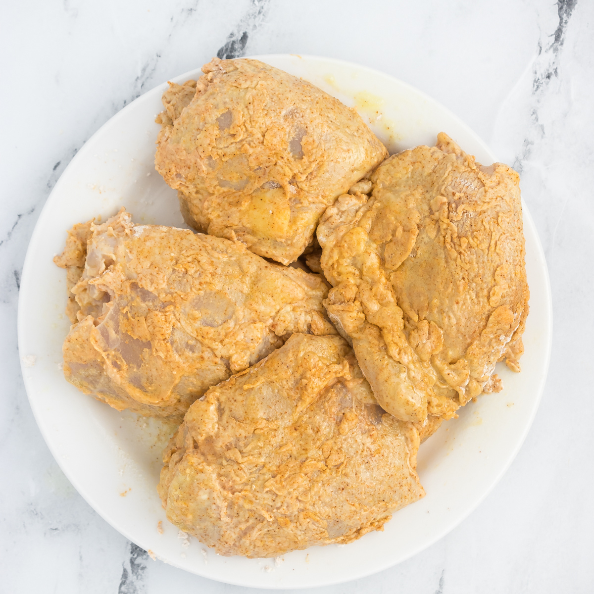 Chicken thighs air frying at 400°F, flipped halfway through, until crispy and cooked to an internal temperature of 165°F using a meat thermometer.