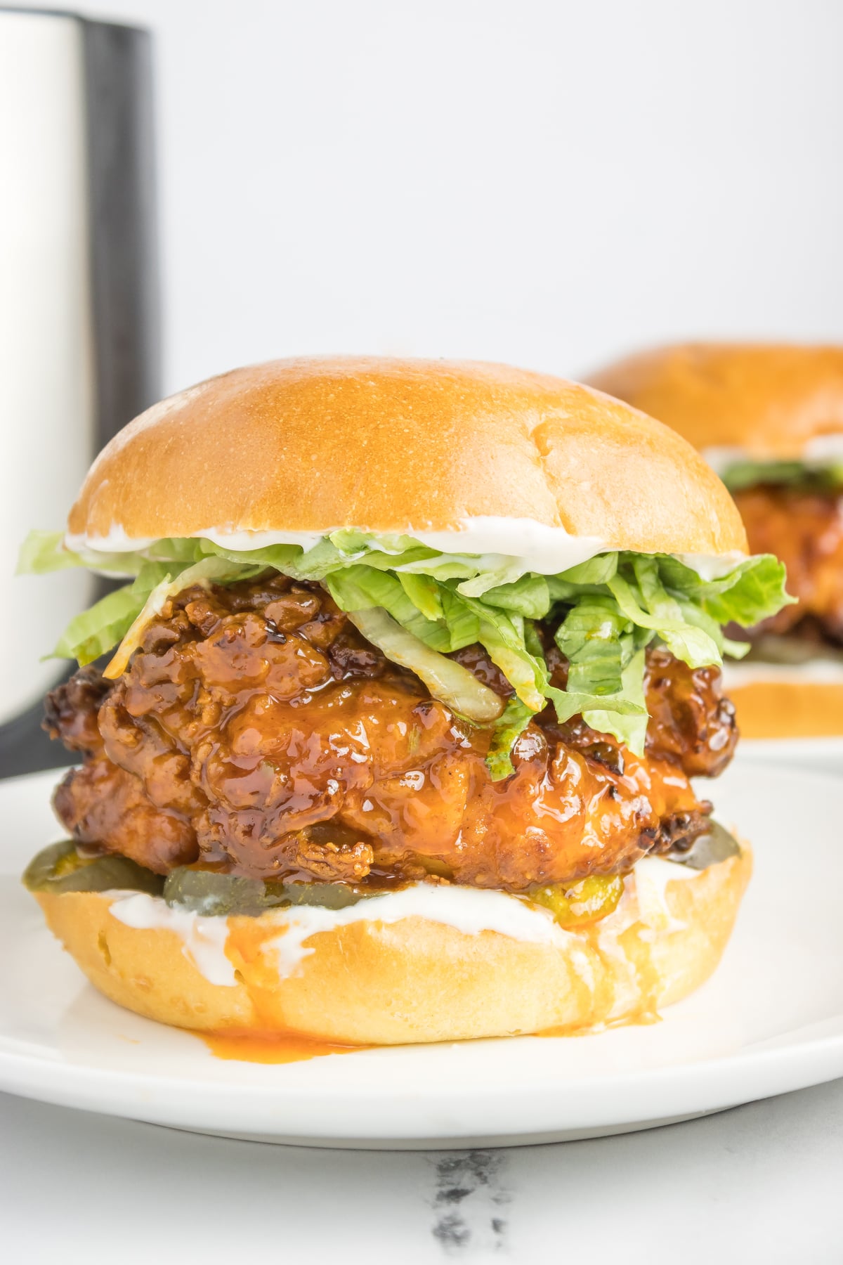 Crispy air fryer chicken brushed with hot honey sauce, placed on a bun with pickles, lettuce, and topped with another bun to complete the sandwich.