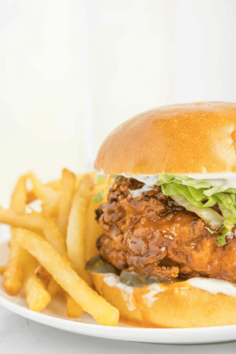Air Fryer Hot Honey Chicken Sandwich with crispy chicken, pickles, lettuce, and a drizzle of hot honey sauce on a bun.