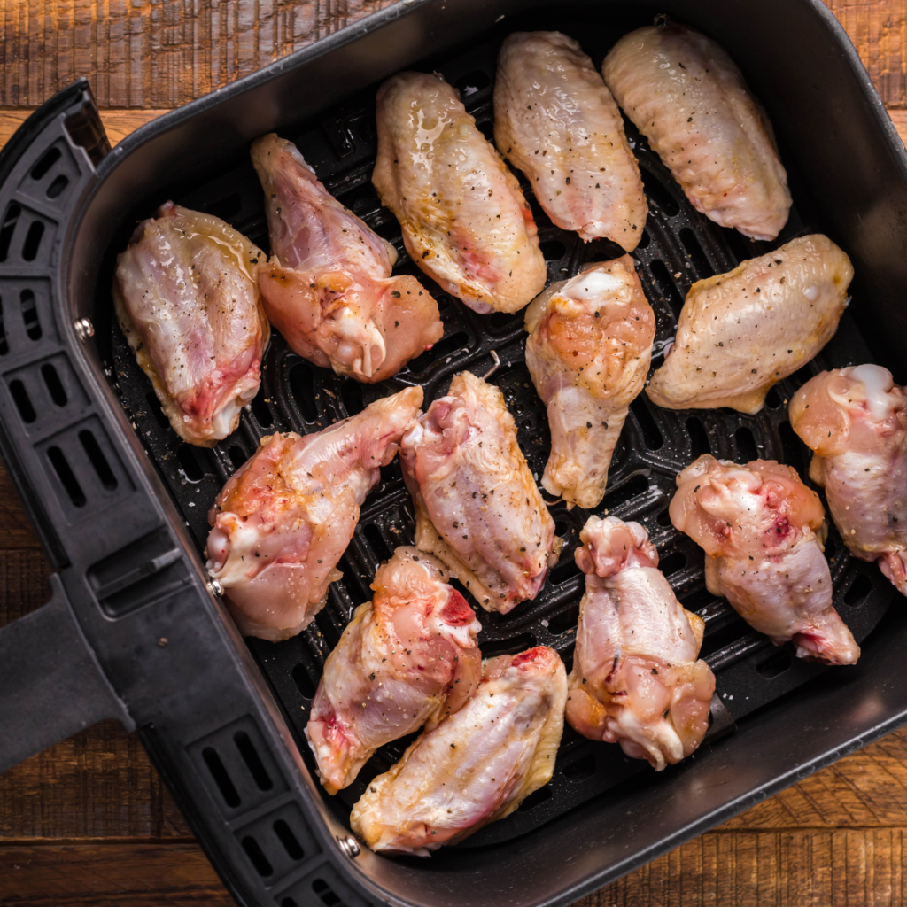 Coated wings in the air fryer basket. Seasoning showing and glaze.