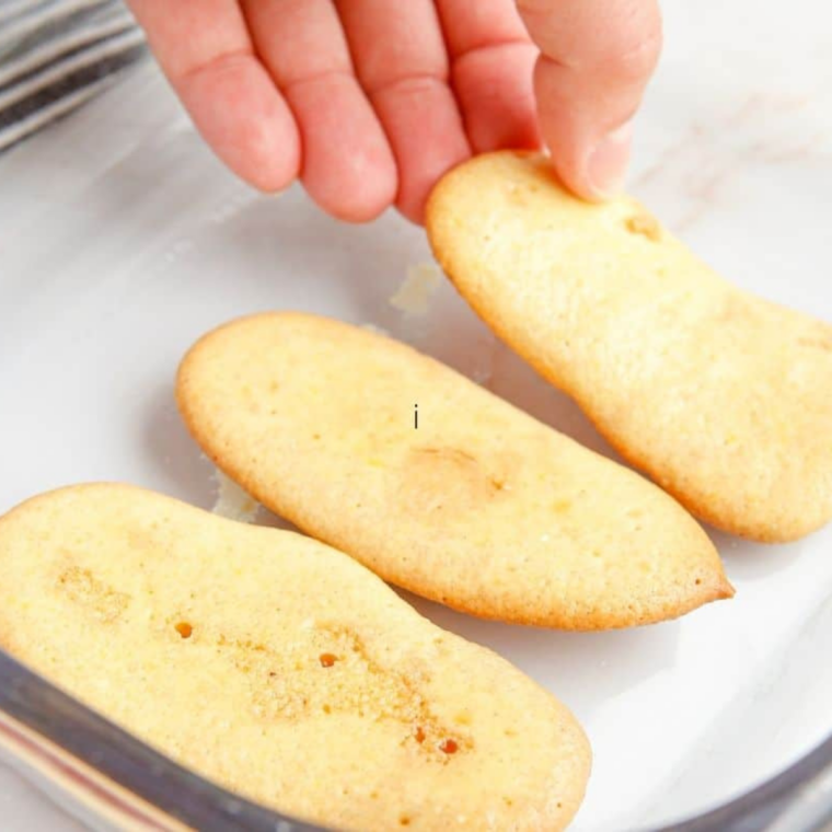 Espresso-soaked ladyfingers arranged in a second layer over mascarpone cream in a square baking dish