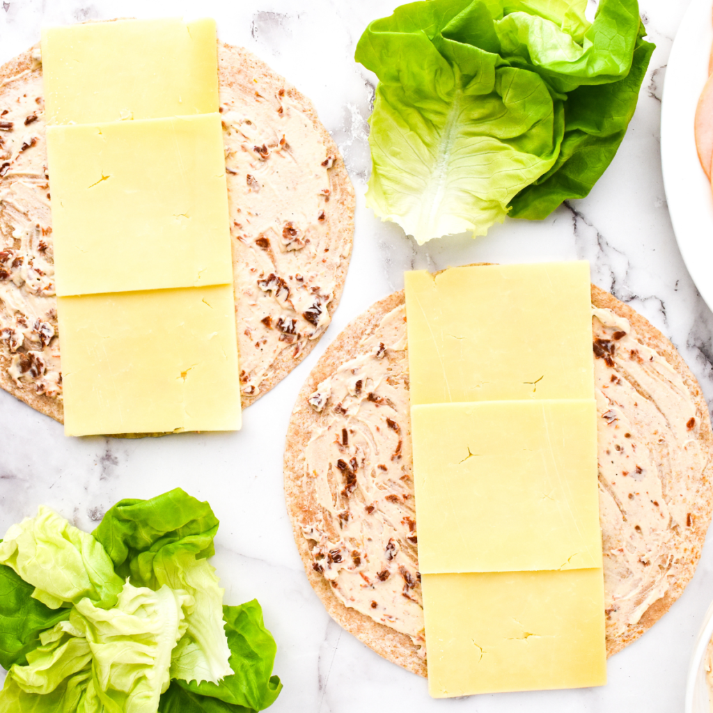 Tortilla rolled tightly, sliced into 1-inch pinwheels, and placed in an air fryer basket, ready to cook until cheese is melted and golden.