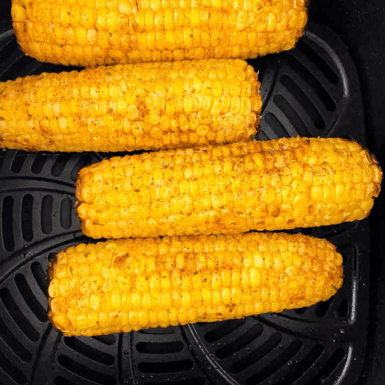 Coating Air Fryer Cajun Corn with melted butter and seasoning.