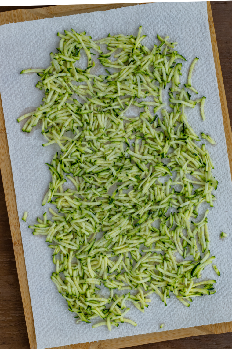 grated zucchini being salted and squeezed in towel to remove moisture for crispy air fryer zucchini burgers