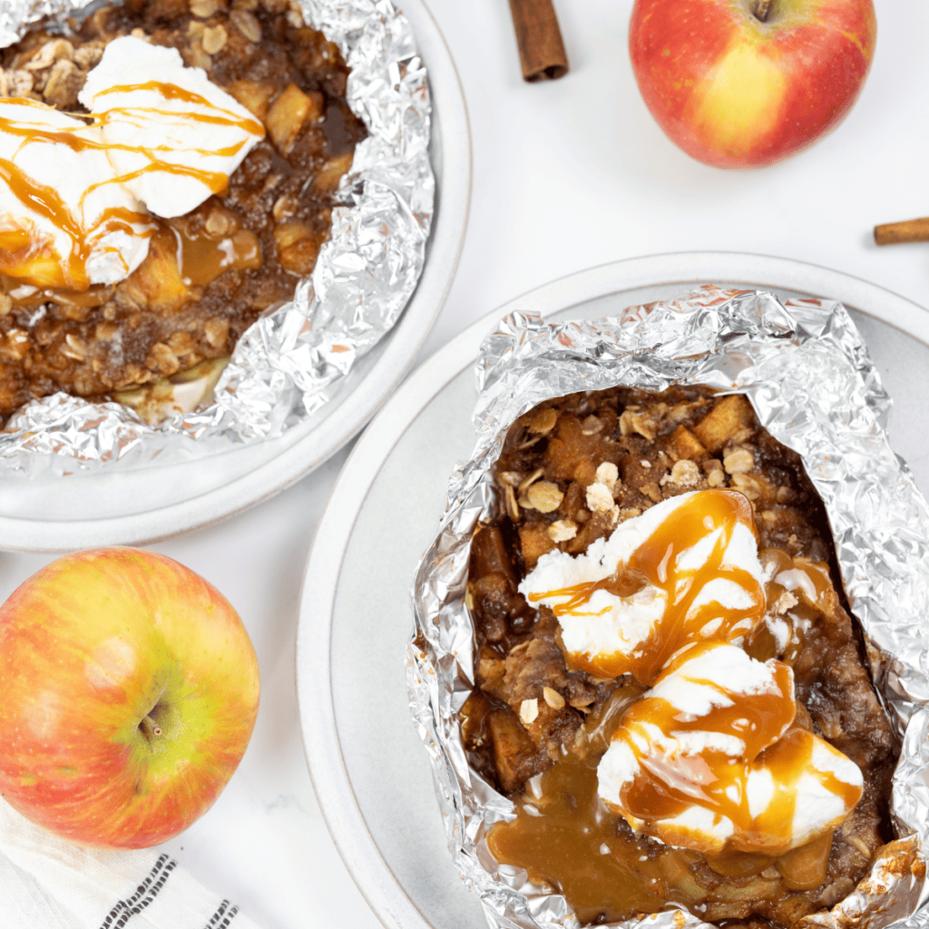 Warm Blackstone apple cobbler served after cooking, topped with vanilla ice cream and caramel sauce.