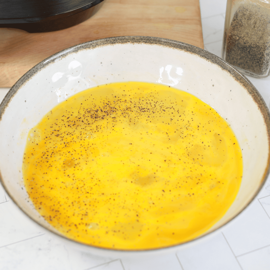 Eggs and heavy cream whisked frothy in a bowl before griddling