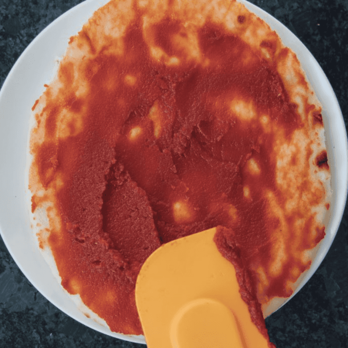 Spread the tomato sauce over the flatbread crust.