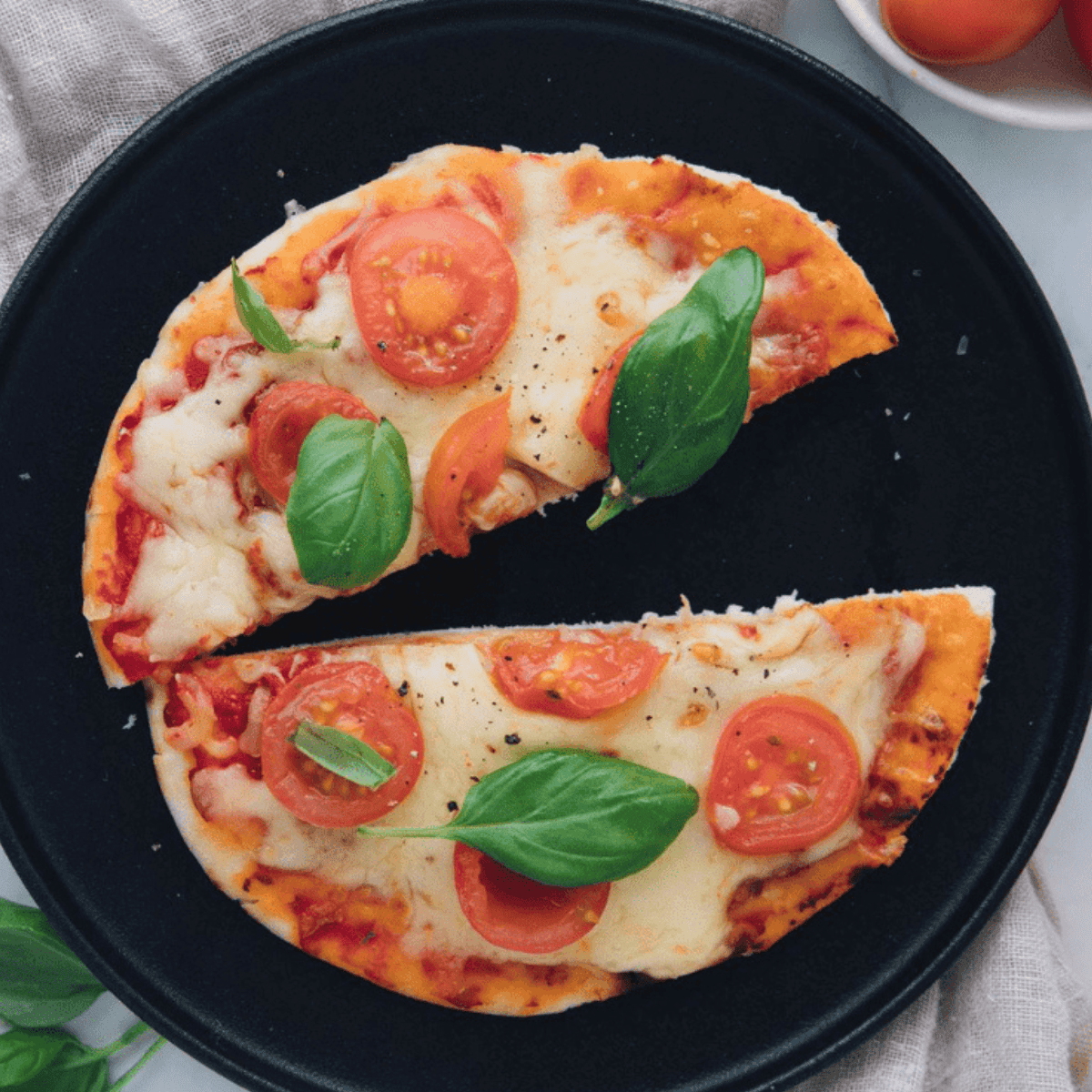 Cheesecake Factory Margherita Flatbread Pizza with crispy flatbread, melted mozzarella, fresh tomatoes, and basil leaves.