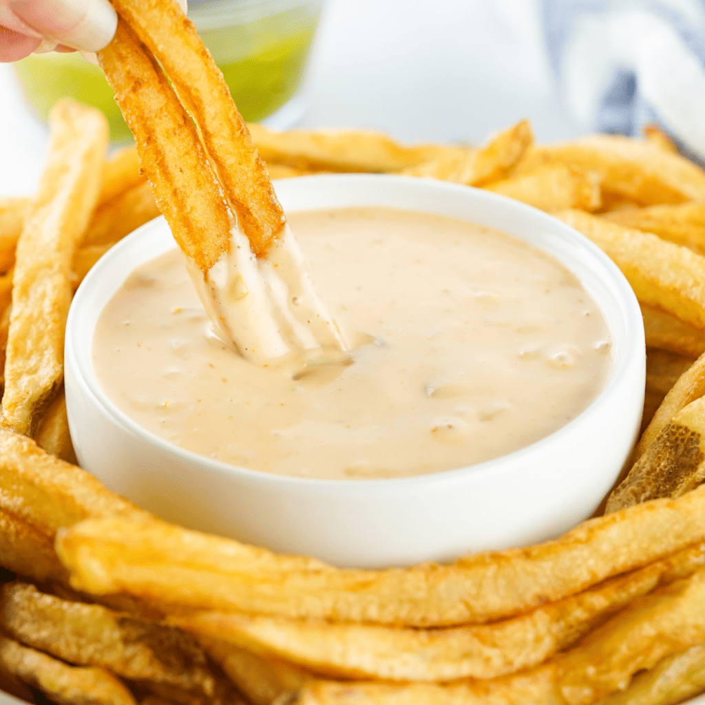 A plate of perfectly cooked air-fried Ore Ida Golden Fries with a side of dipping sauce.