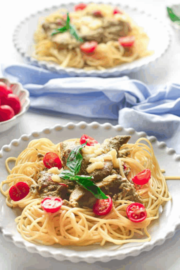 Bowl of Instant Pot pesto chicken pasta with tender chicken, pasta, and creamy green pesto sauce, garnished with Parmesan and herbs