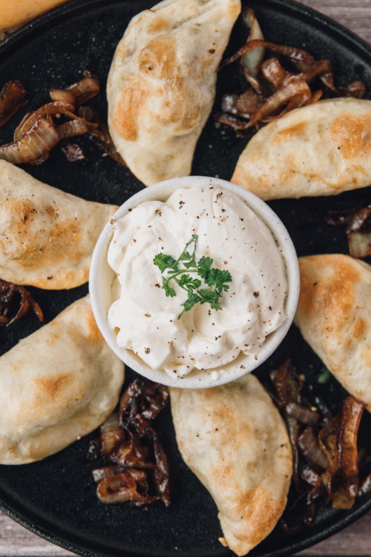 Freshly made potato and cheese pierogies served with butter, caramelized onions, and a side of sour cream.