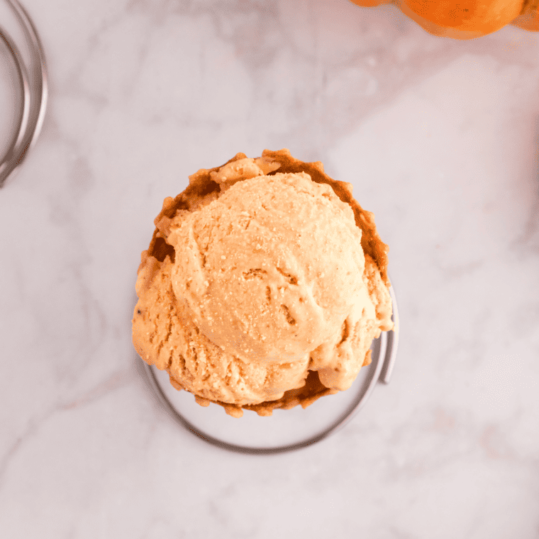 Scoop of pumpkin ice cream drizzled with maple syrup and crushed cookies
