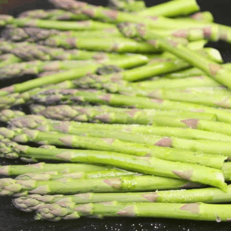 Brushing olive oil on Ninja Foodi Grill grates to prevent asparagus from sticking.