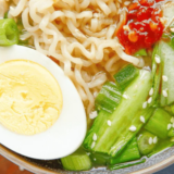 slow cooker chicken ramen with shredded chicken, soft boiled egg and nori in a dark bowl