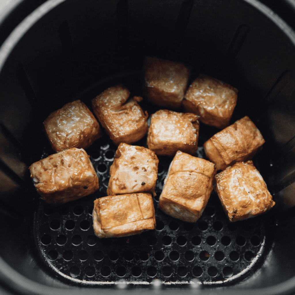 Agedashi Tofu being placed in the air fryer - "Placing seasoned tofu cubes into the air fryer basket for cooking."