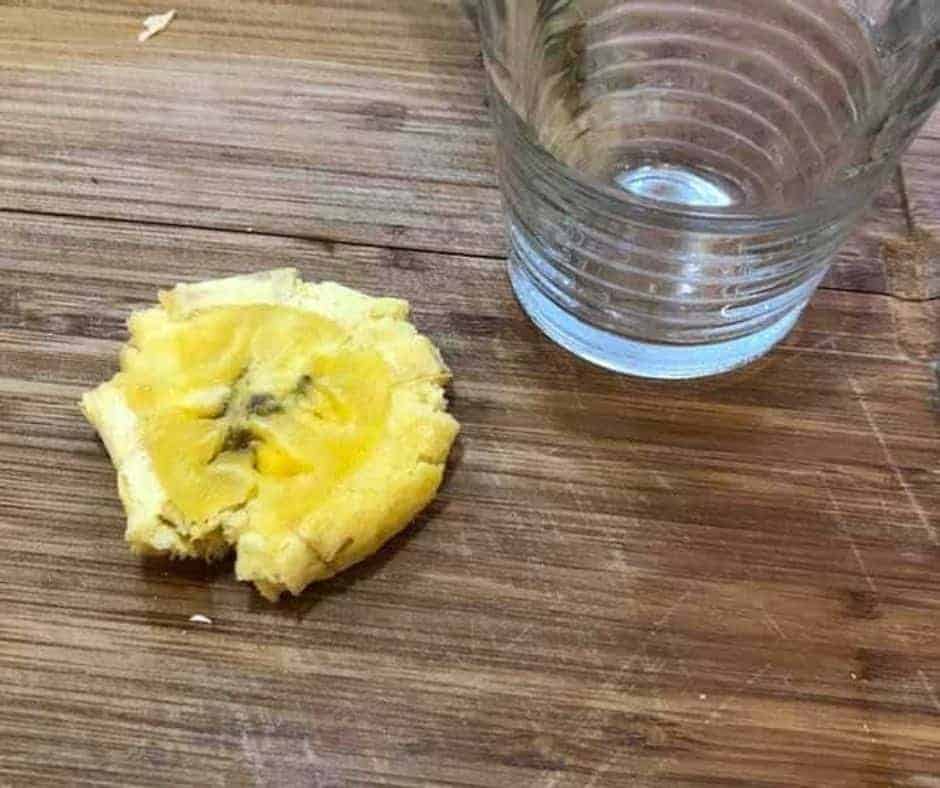 overhead: smashed air fried tostone next to a glass drinking glass