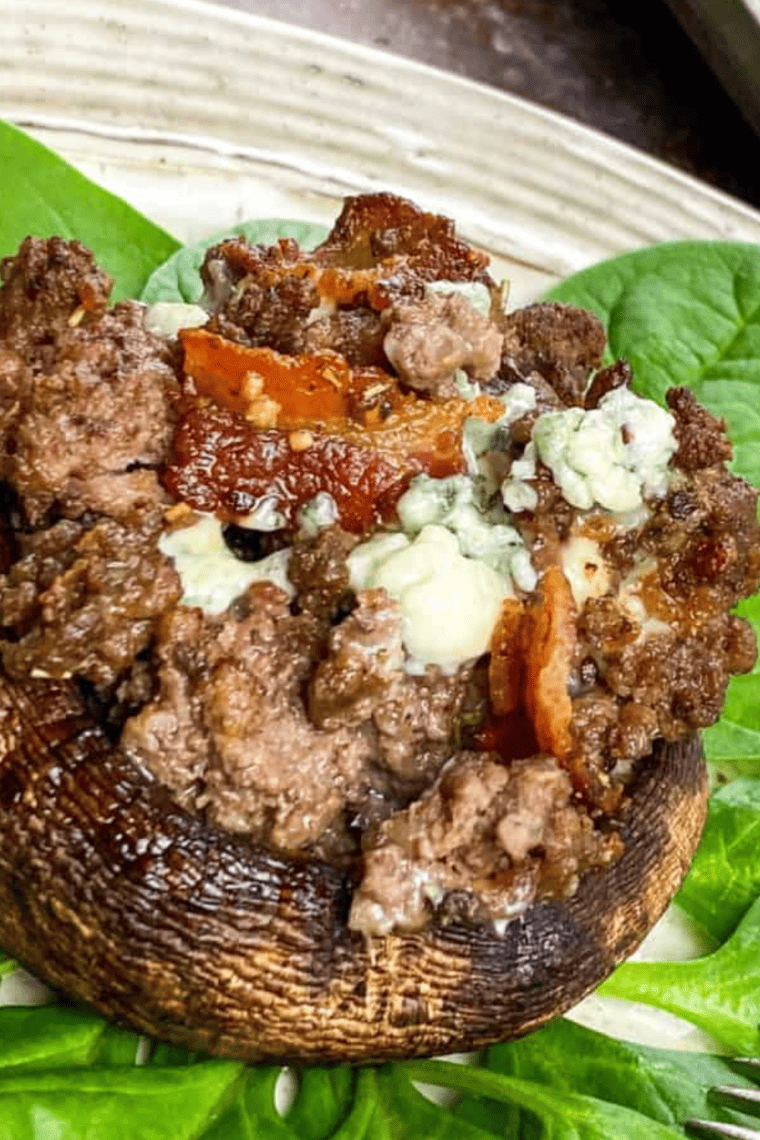 Golden-brown air fryer stuffed mushrooms filled with crispy bacon and tangy blue cheese, served on a white plate.