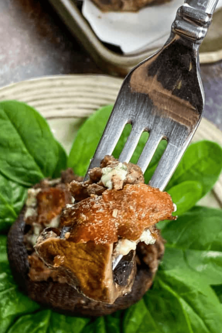Golden-brown air fryer stuffed mushrooms filled with crispy bacon and tangy blue cheese, served on a white plate.