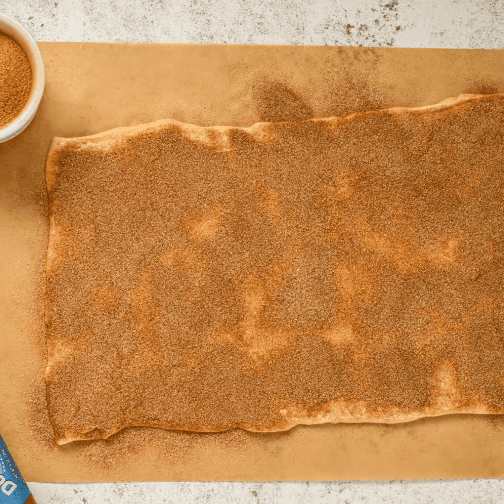 Rolling out the croissant dough for Cruffins: A person rolling out croissant dough on a floured surface.