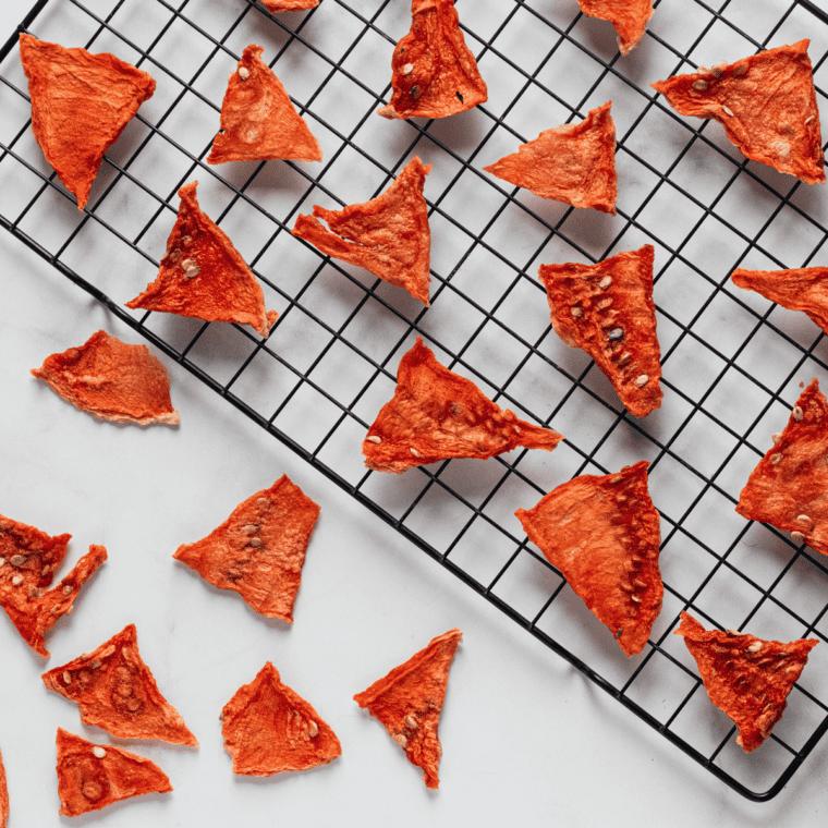 Partially dried watermelon slices on the air fryer tray, flipped halfway through