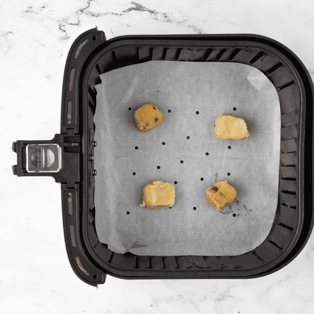 Step-by-step process of placing frozen cookie dough in the air fryer.