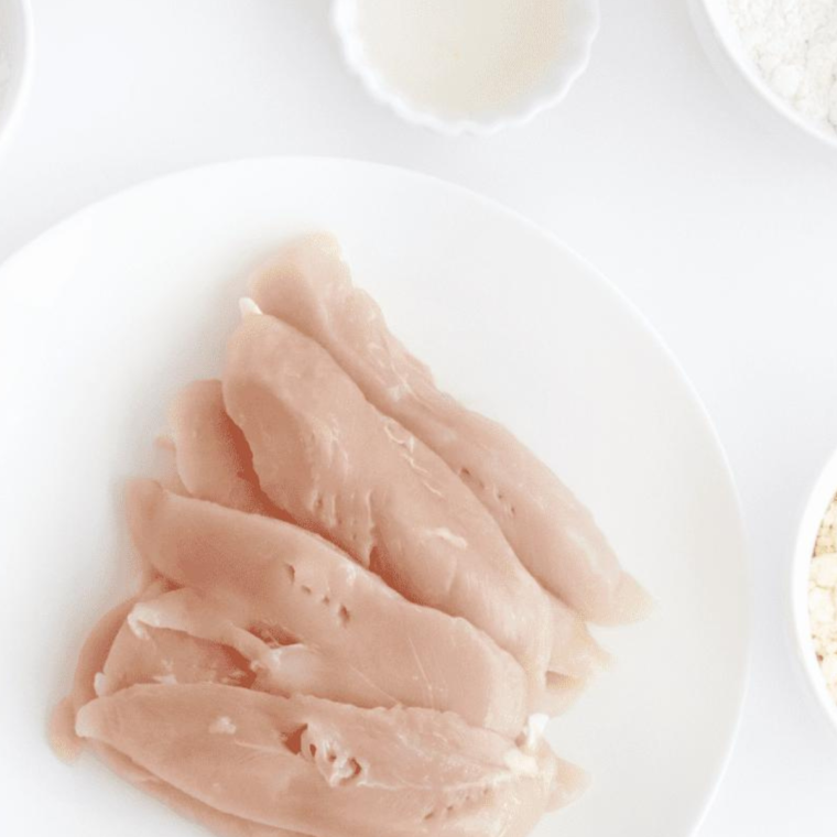 Marinating chicken tenders in a bowl with honey and garlic mixture, preparing for air frying.