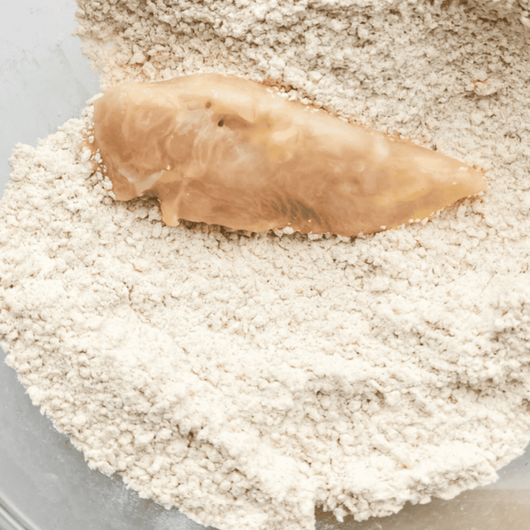 Coating chicken tenders with breadcrumbs, ready to be placed in the air fryer basket.