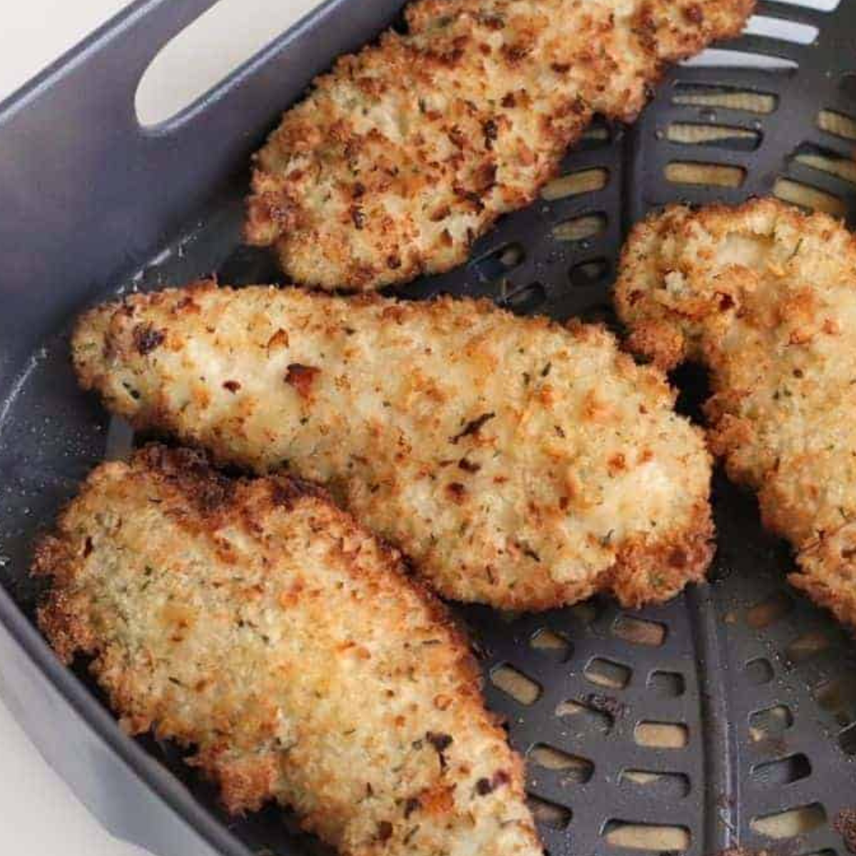 Removing crispy honey garlic chicken tenders from the air fryer, ready to be served.
