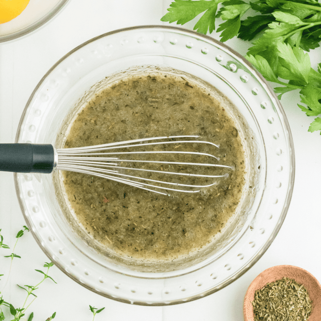 Mixing lemon juice, olive oil, garlic, herbs, salt, and pepper in a small bowl to create the marinade.