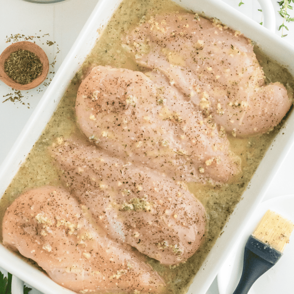 Marinating chicken breasts in a Ziploc bag with lemon marinade, refrigerating for flavor infusion.