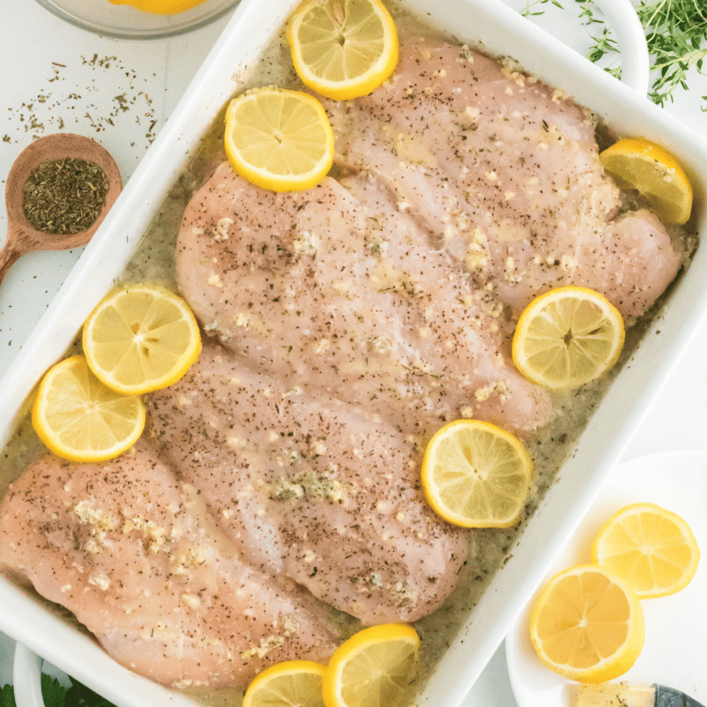 Preheating the air fryer to 370°F and placing marinated chicken breasts in the basket for even cooking."