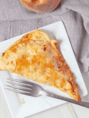 "Golden, crispy air fryer peach pie with a flaky crust and sweet peach filling on a white plate."