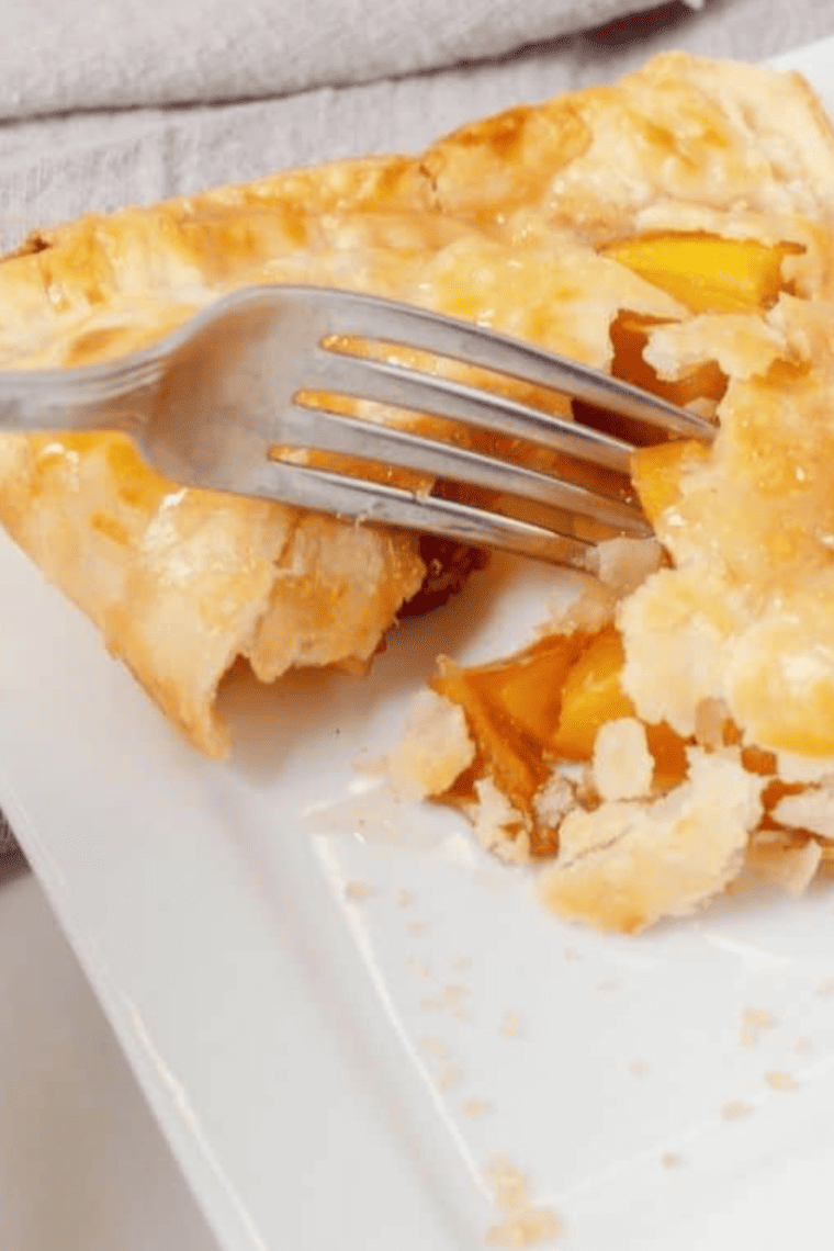 Golden, crispy air fryer peach pie with flaky crust and sweet peach filling on a plate.
