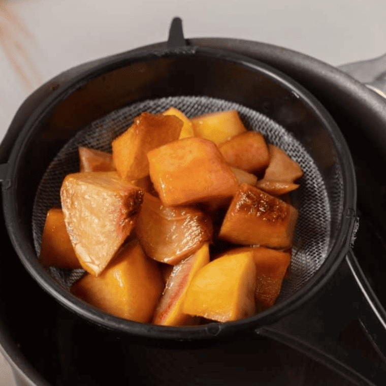 Peach juice being drained into a saucepan, whisked with cornstarch, cinnamon, and salt to combine.