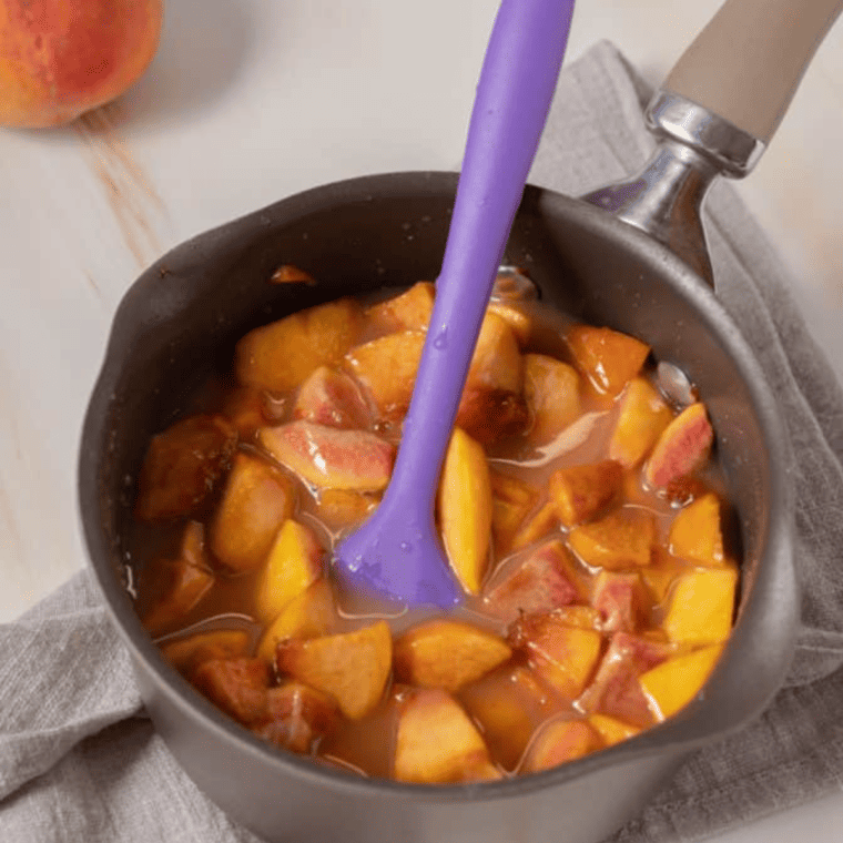 Simmering peach mixture in a saucepan, thickening into syrup, then adding lemon juice, almond extract, vanilla, and folded peaches.