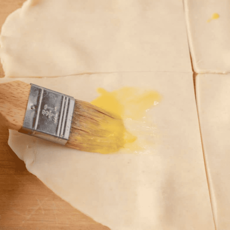 Pie dough being unrolled on a floured surface, then cut into four equal sections.