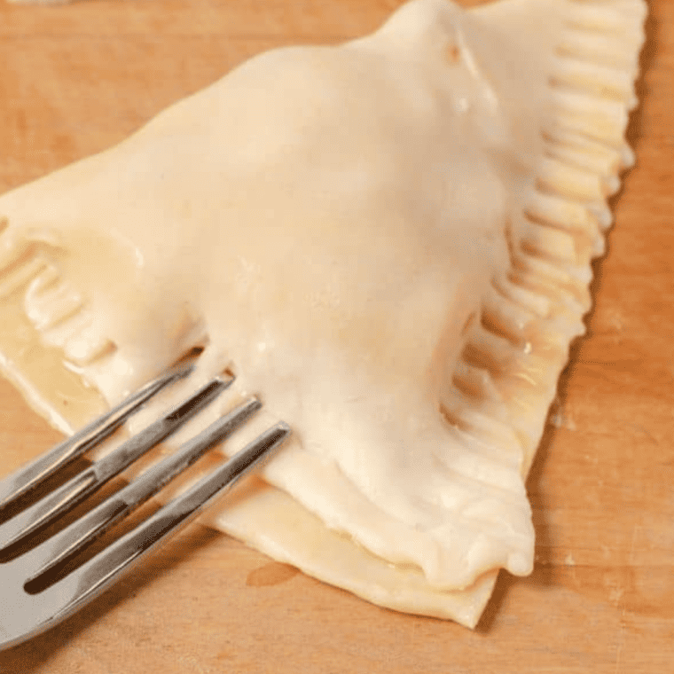 Pie dough folded into pockets, edges pressed with a fork to seal.