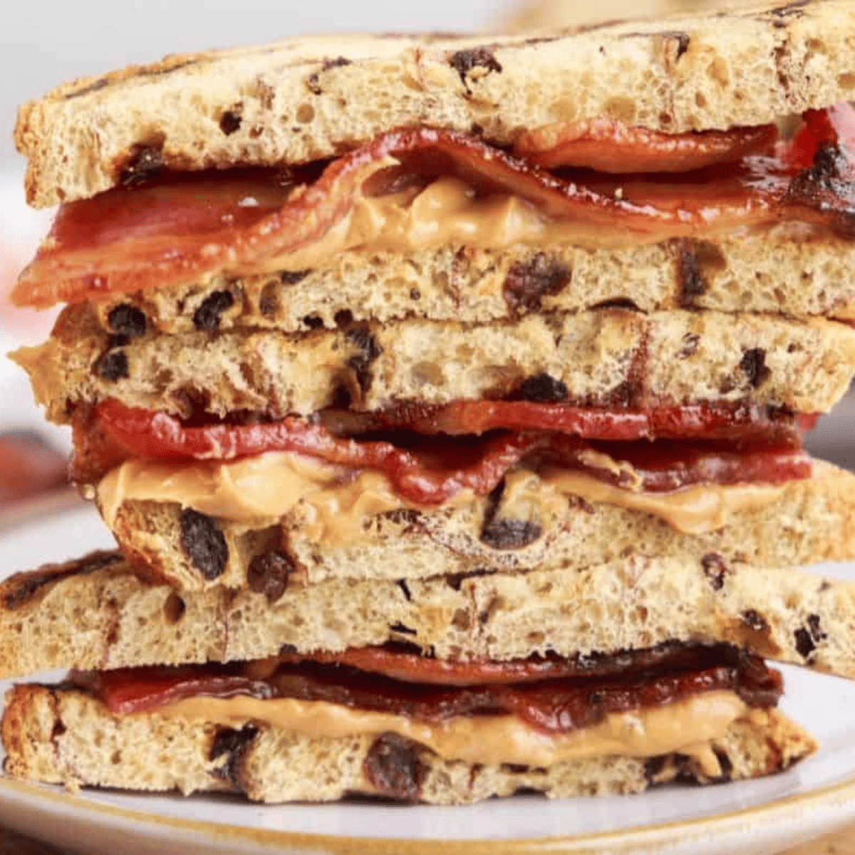A crispy Air Fryer Peanut Butter and Bacon Sandwich served on a plate, oozing with peanut butter and layered with caramelized bacon.