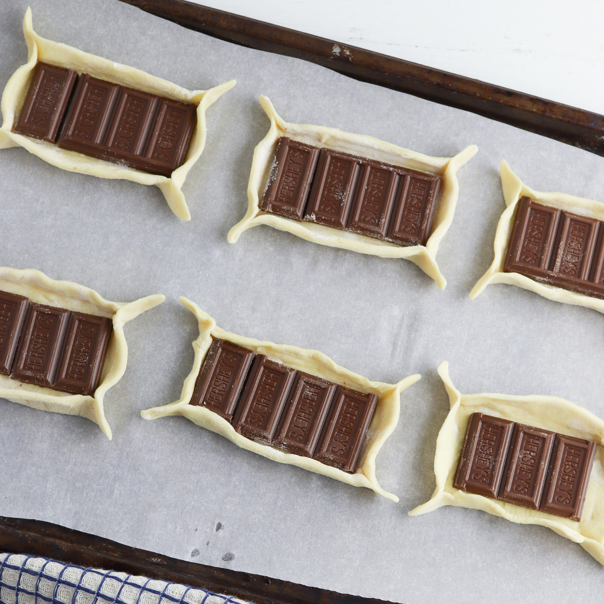 Puff pastry squares filled with chocolate, folded into triangles and sealed around the edges to form s’mores bites, ready for the air fryer.