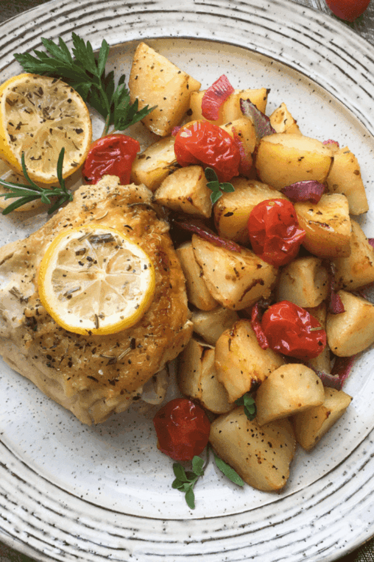 Golden-brown air fryer roasted potatoes with juicy cherry tomatoes, served on a plate.
