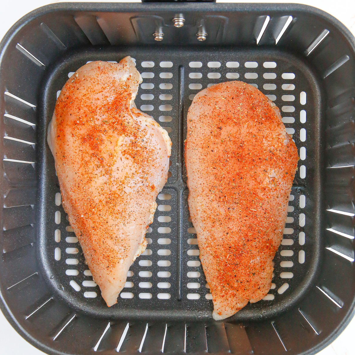 Cooking the chicken in the air fryer basket.