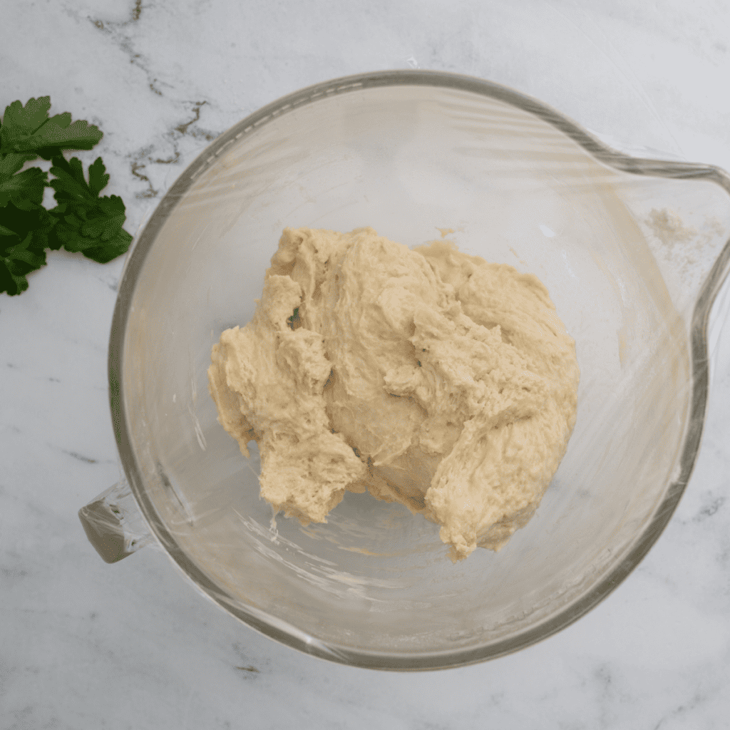 Dough divided into 8 portions, flattened with a rolling pin, brushed with olive oil, and set to rise on a plate covered with plastic wrap or a kitchen towel
